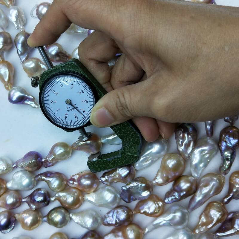 Measuring the thickness and size of large freshwater baroque pearl with a dial gauge